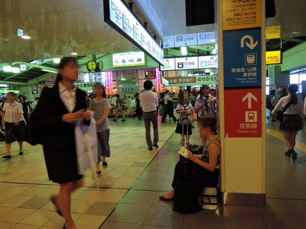品川駅のコンコースでたくさんの荷物と共に待っている旅人